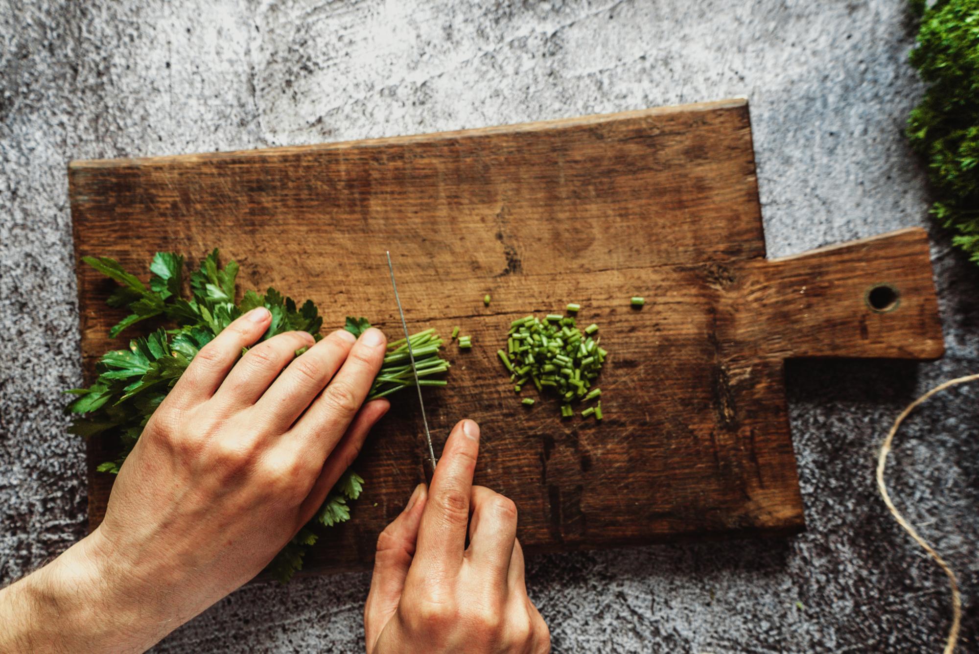 Hands seasoning food over wooden board